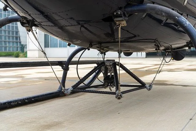 A close-up view of the dark blue helicopter's belly and skid landing gear, showing structural details.