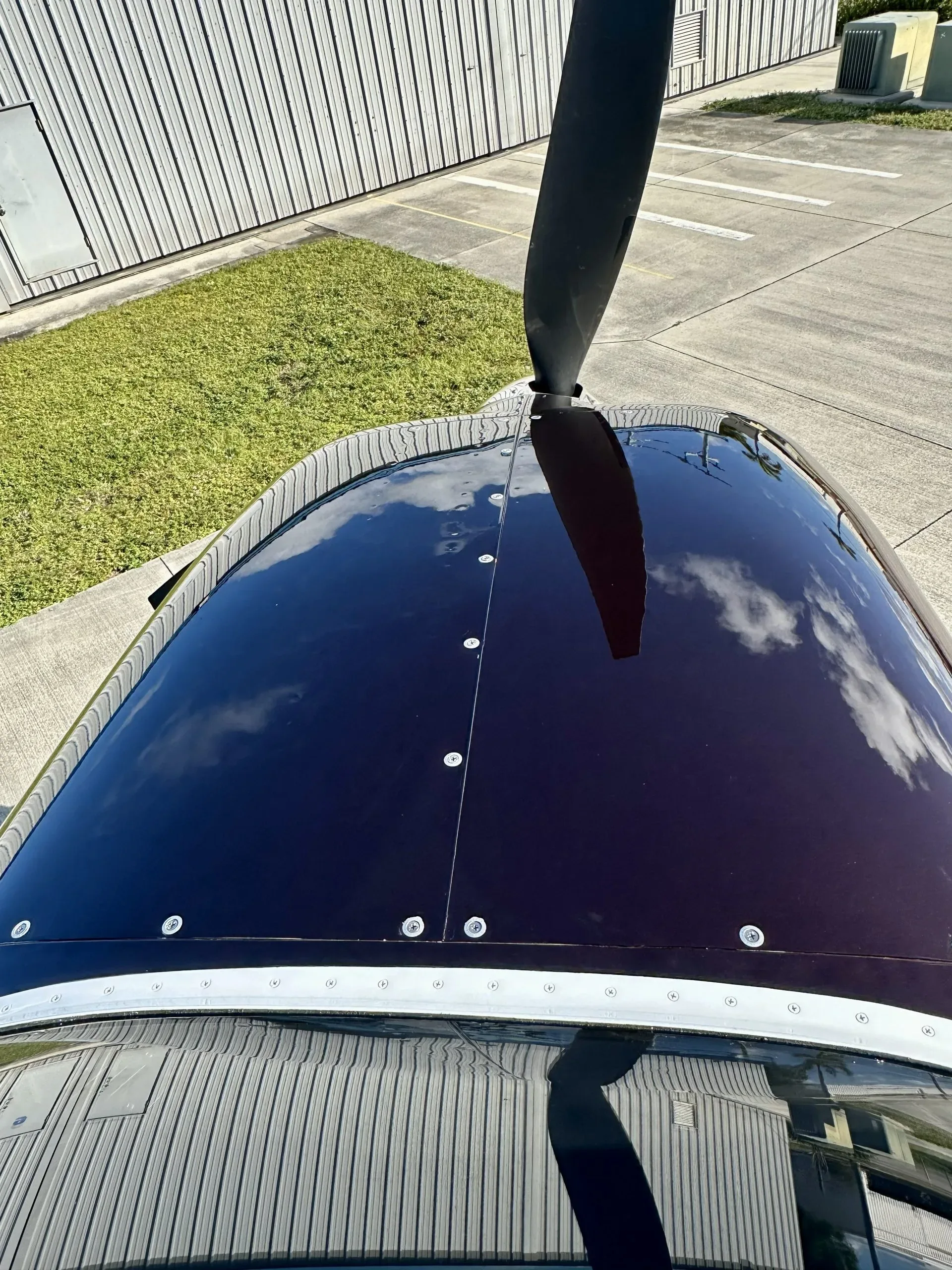 An overhead view of the glossy dark brown engine cowling, reflecting clouds and a building.