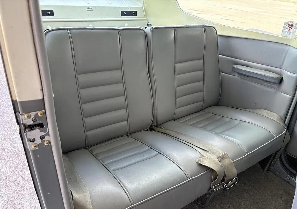 Close-up view of the two gray rear passenger seats with seatbelts in the aircraft cabin.
