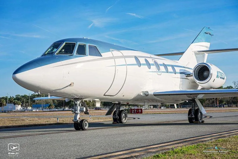 A front-side view of the white and blue business jet N786CM on an airport tarmac.
