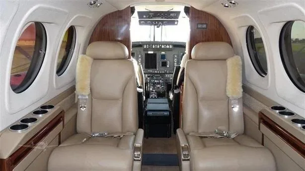 The passenger cabin of a Beechcraft King Air 350i, showing beige leather seats and wood paneling.