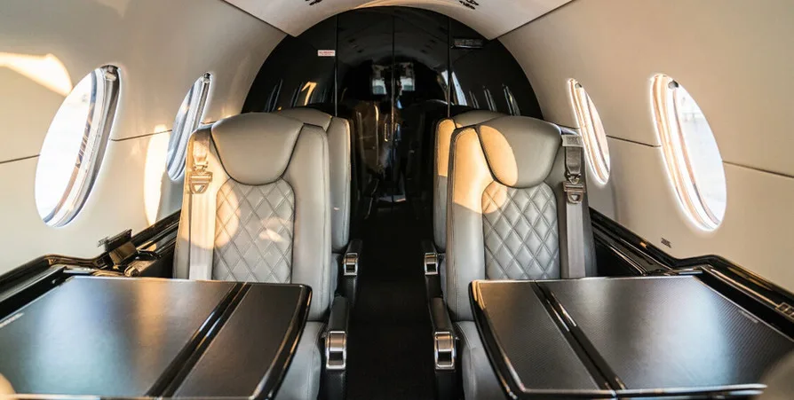 Interior view of the aircraft cabin showing leather seats and tables.