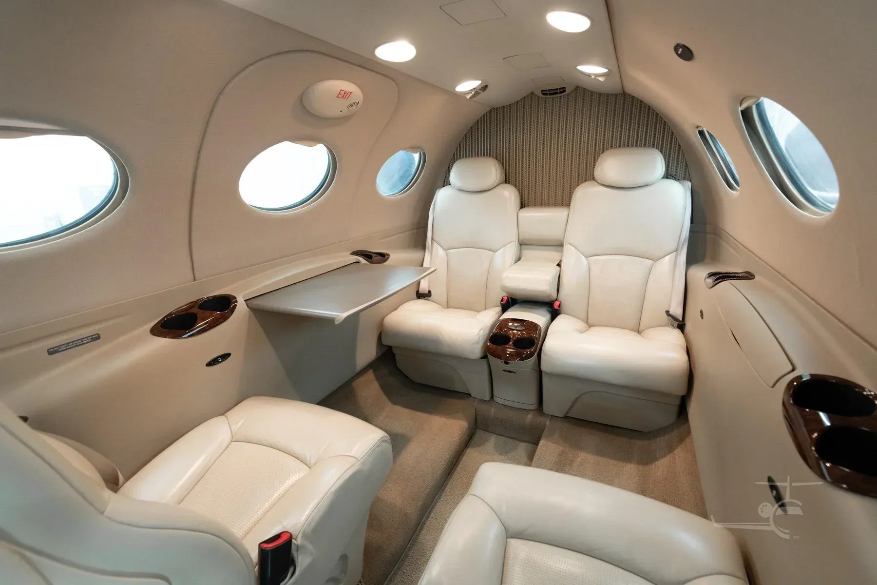 The beige leather interior cabin of a Cessna Citation M2, featuring club seating and a small table.