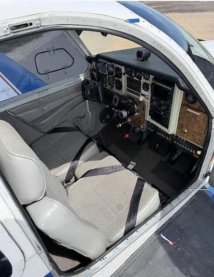 The aircraft's cockpit and front cabin area, showing the instrument panel and two grey seats.