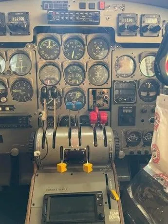 A detailed view of an aircraft cockpit with numerous analog gauges and a central throttle quadrant.