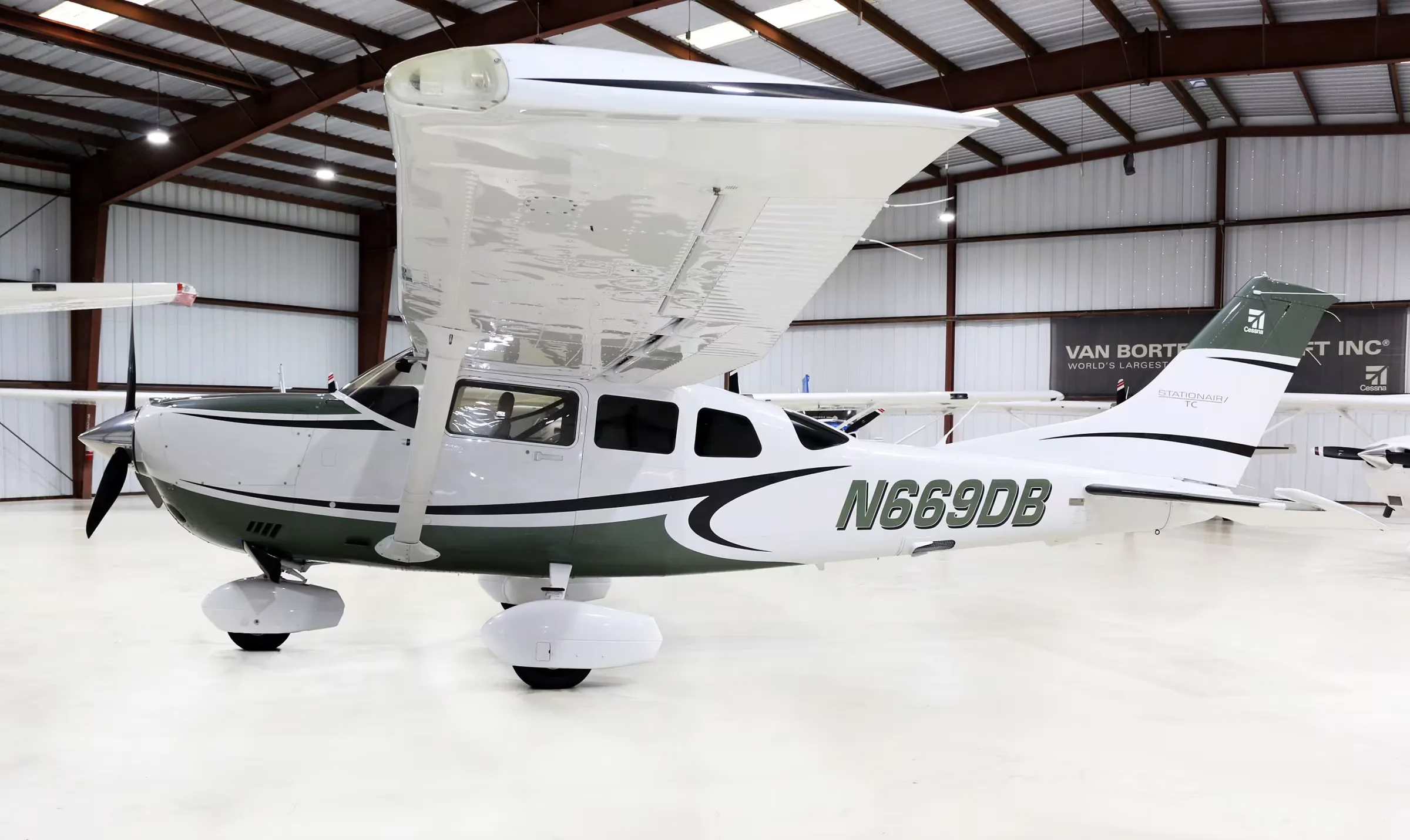 Side view of a white and green Cessna Stationair TC, registration N669DB, parked in a hangar.