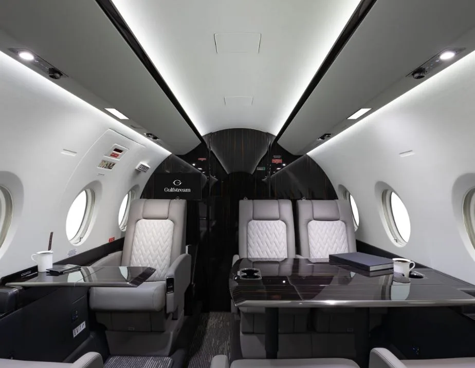 View of the aircraft cabin with leather seats and dark wood accents.