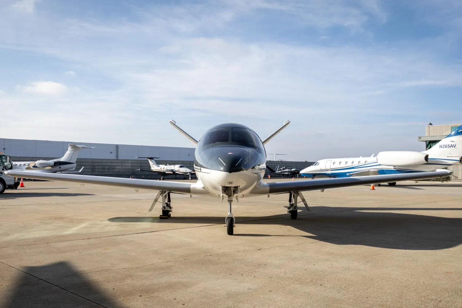 A front view of a white and dark grey Cirrus Vision Jet (N82WF) parked on an airport tarmac.
