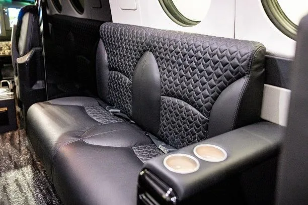 A close-up view of black quilted leather passenger seats inside an aircraft cabin.