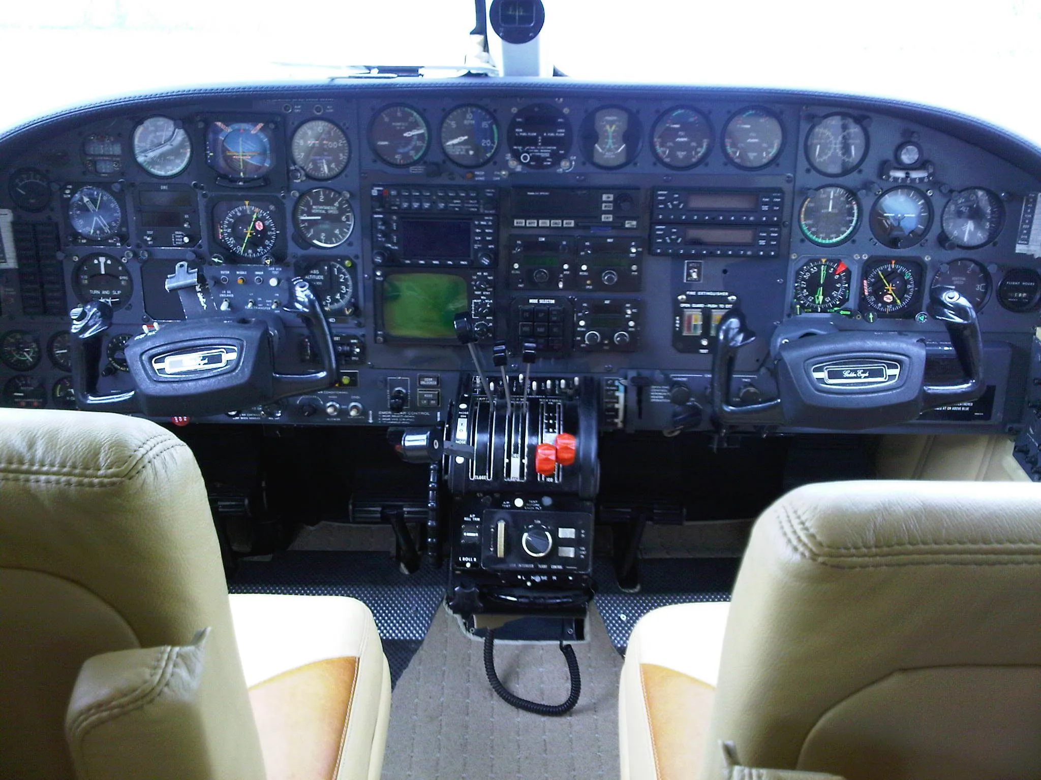 A full view of an aircraft cockpit from the pilot's perspective, featuring the instrument panel, yokes, and throttle quadrant.