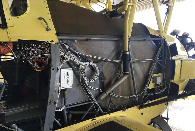 Exposed internal wiring and structural components of the yellow biplane's fuselage.