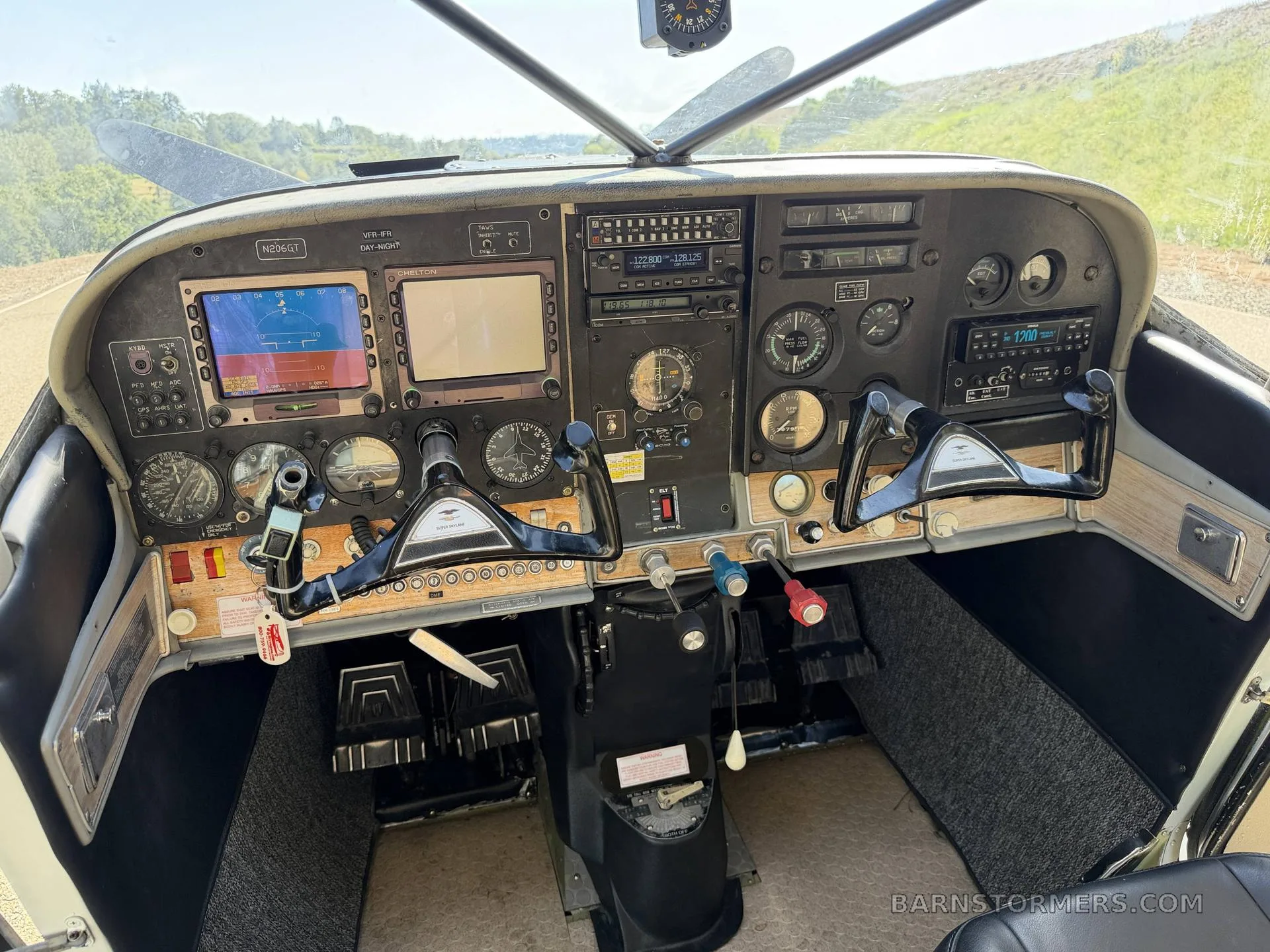 The cockpit of a Cessna 206GT showing the instrument panel with dual yokes, avionics, and two large display screens.