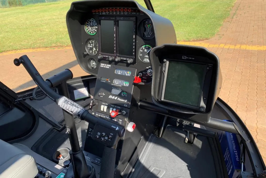 A detailed view of the instrument panel and controls inside a Robinson R44 helicopter cockpit.