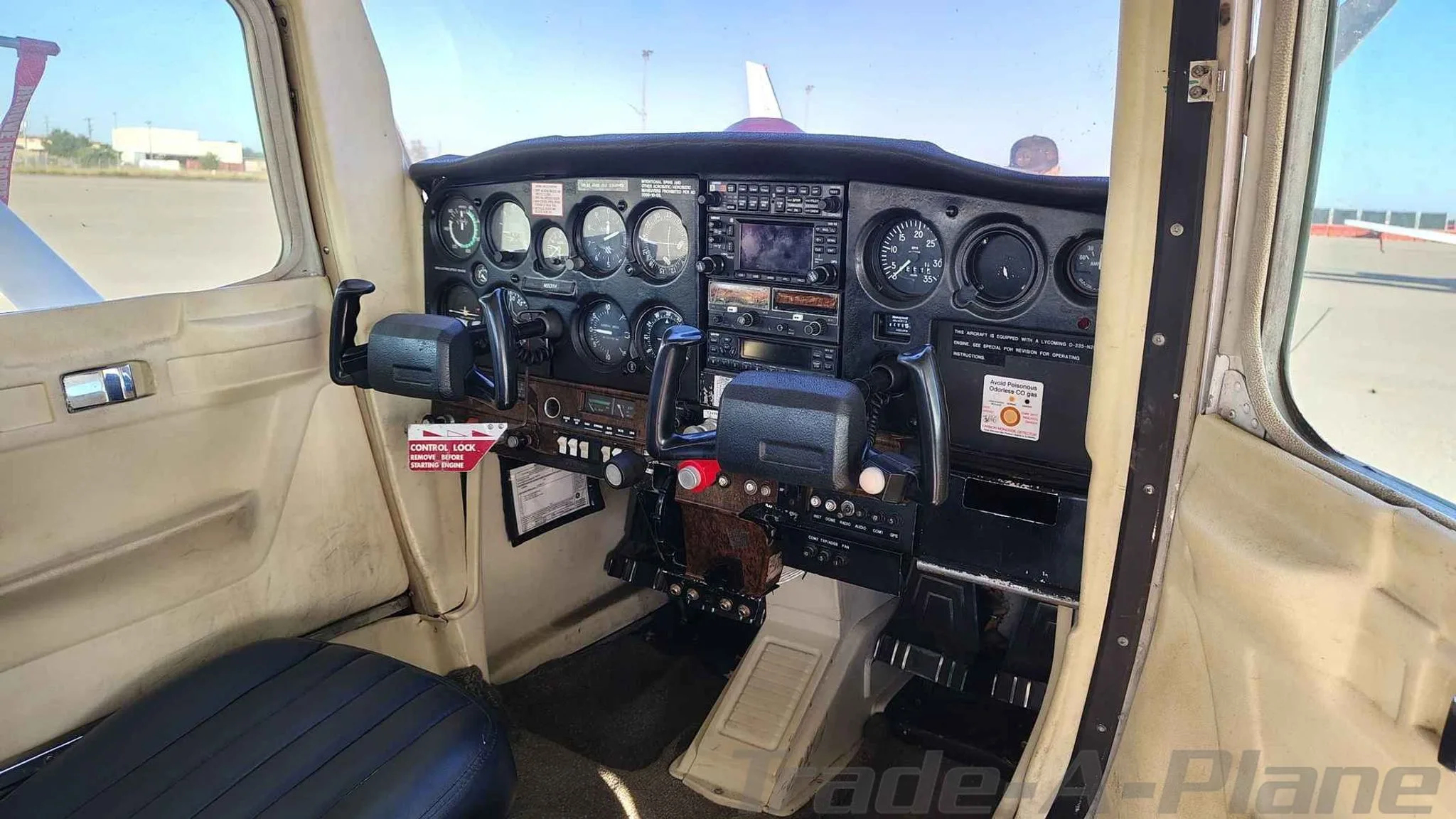 The cockpit of a small aircraft, showing the instrument panel, yokes, and controls from the pilot's seat.