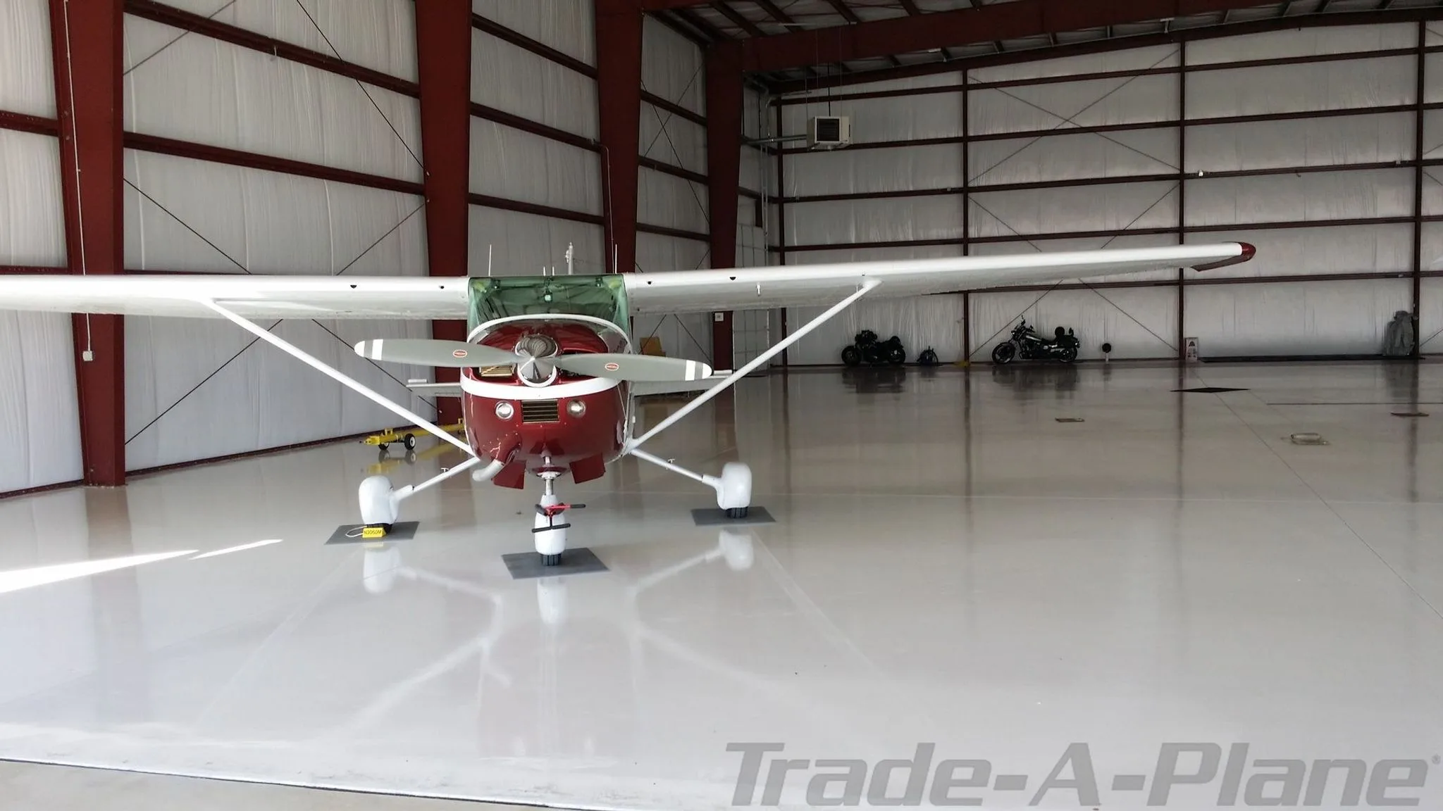 A white and maroon Cessna aircraft, N306DM, viewed from the front inside a large hangar.