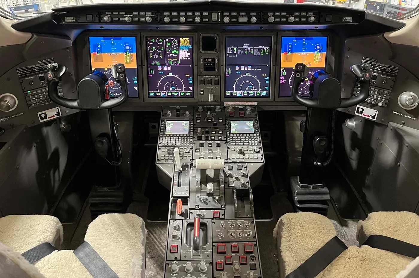The modern cockpit of a business jet with multiple digital displays and control yokes.