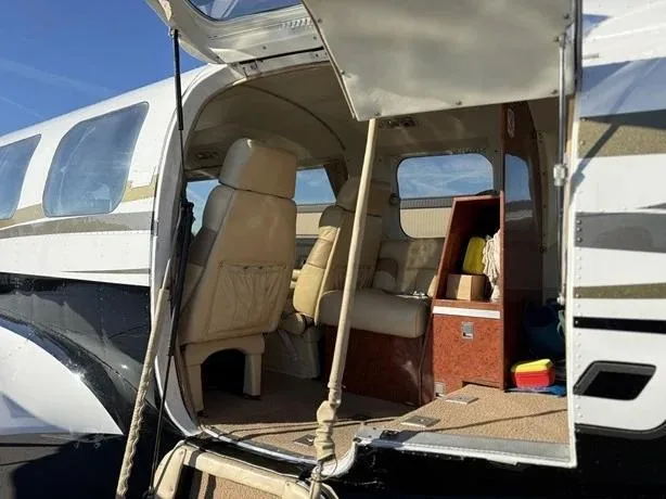 The open passenger door reveals the aircraft's light-colored cabin interior with seating and storage.