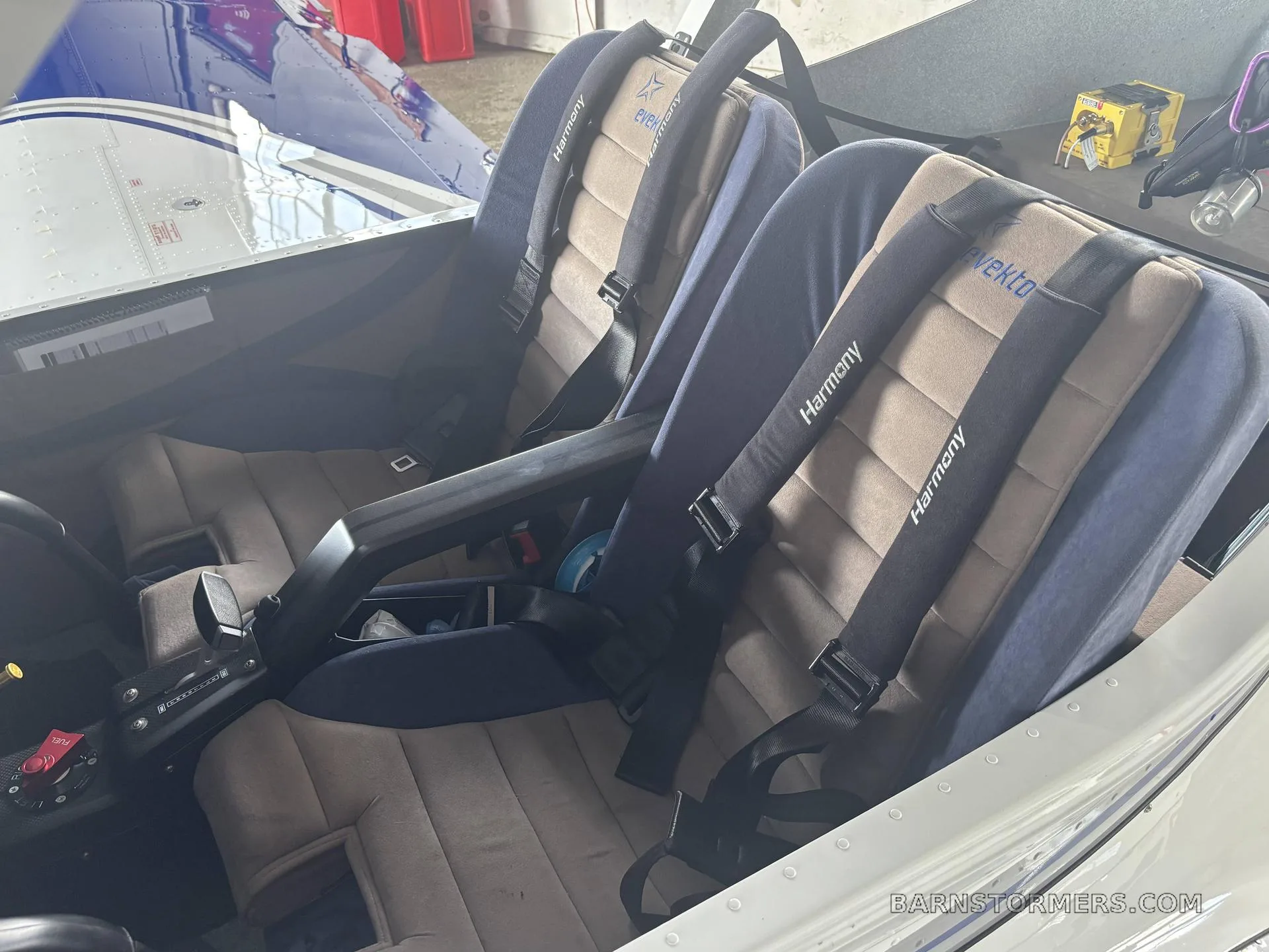 The interior cabin of the Evektor Harmony Light Sport aircraft shows two tan and blue seats with "Harmony" branded harnesses.