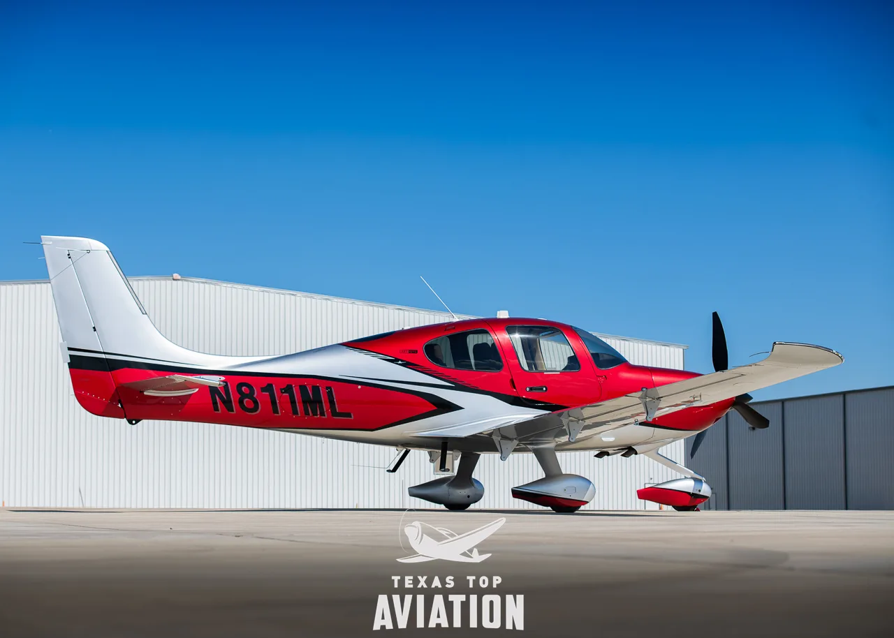 A red and silver Cirrus SR22T GTS aircraft with registration N811ML parked on an tarmac in front of a hangar.