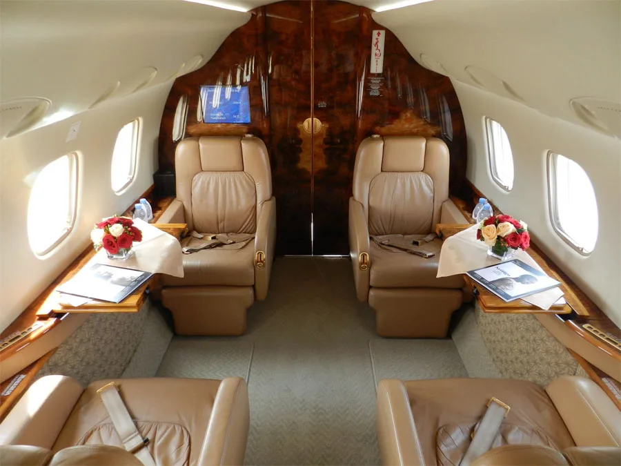 The luxurious interior of an aircraft cabin features two large leather seats and polished wood accents.