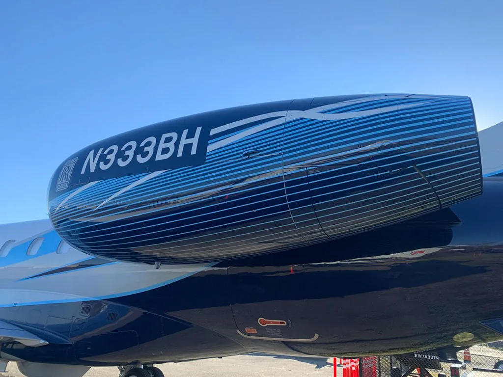 A close-up of the Embraer Legacy 650's engine nacelle, featuring the N333BH registration and blue stripe livery.