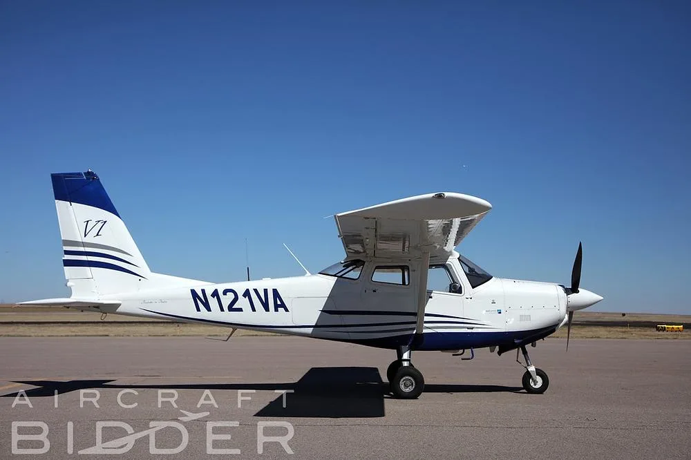 A side view of the white and blue Tecnam P2010 single-engine aircraft, N121VA, parked on an airfield.