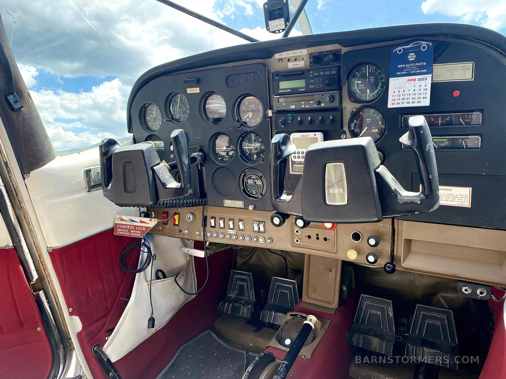 The cockpit of a small aircraft, showing the instrument panel, dual yokes, and red floor.