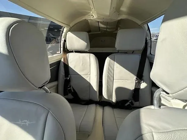 The light-colored leather interior cabin of a small aircraft, showing two rear passenger seats.