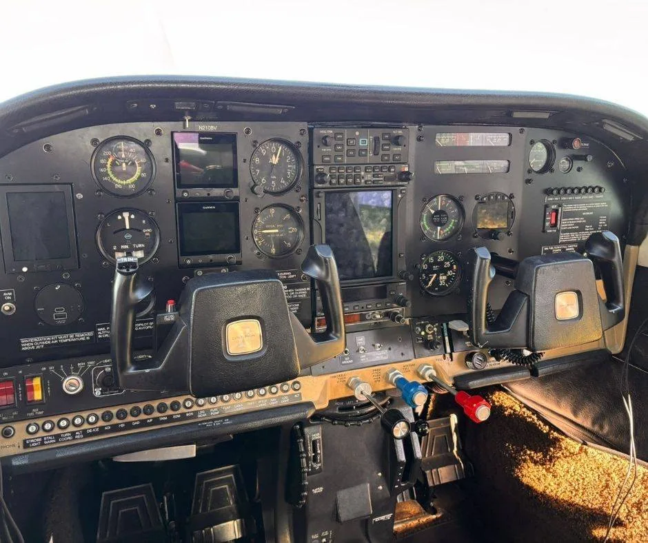 A wide view of the aircraft's cockpit, showing the complete instrument panel, dual yokes, and rudder pedals.