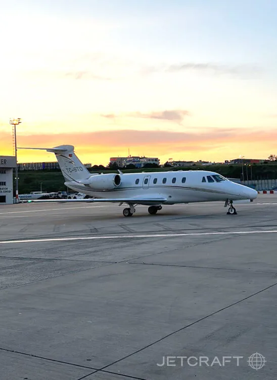 A white Cessna Citation business jet with tail number TC-BTO parked on an airport tarmac at sunset.