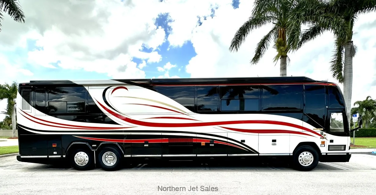 Side view of a Prevost coach with a black, white, and red paint scheme parked outside.