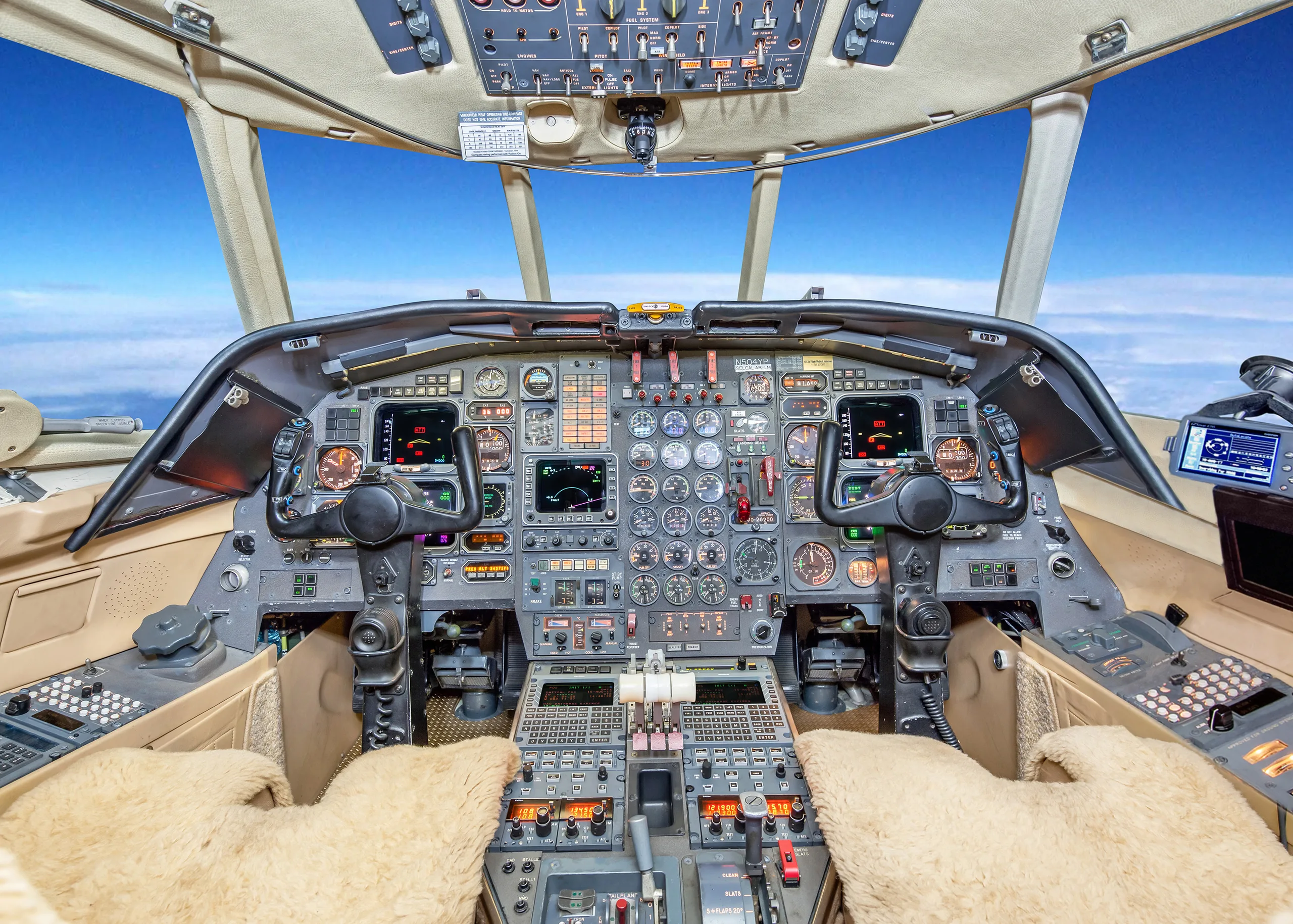 The detailed cockpit of a private jet with multiple screens, gauges, and controls, viewed from the pilot's seat.