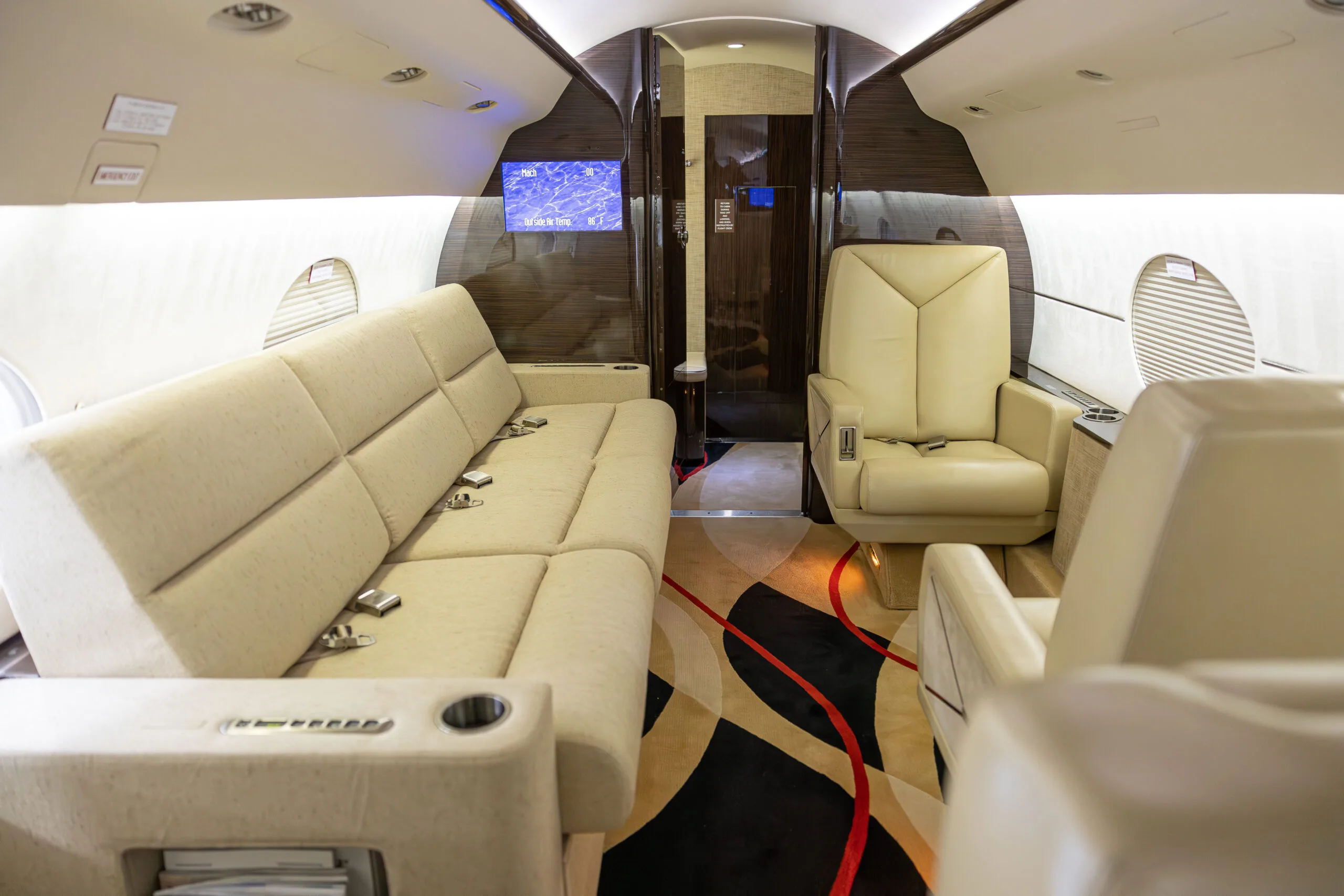 Aircraft interior with a sofa, leather seat, and patterned carpet.