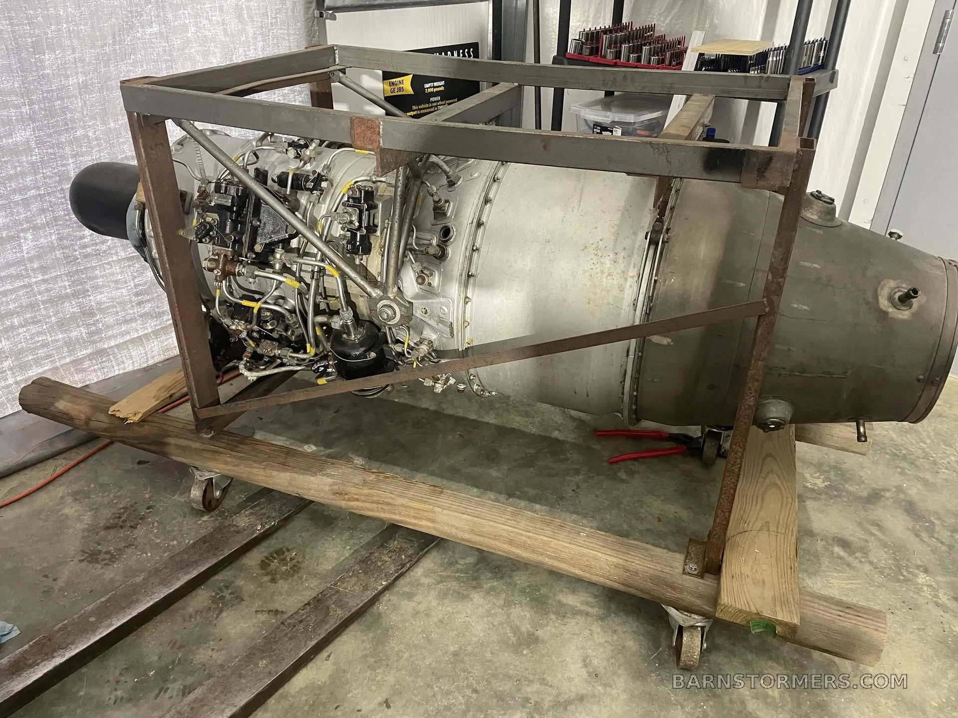 A large aircraft jet engine on a wooden and metal stand in a workshop.
