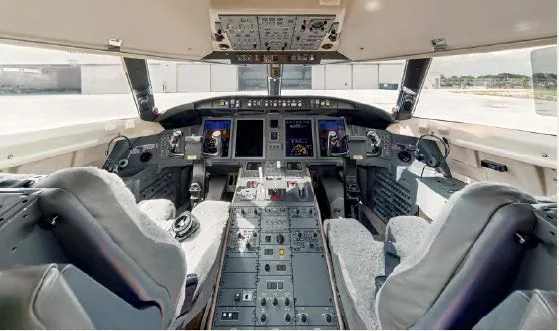 The cockpit of a business jet, showing the instrument panel, control yokes, and pilot seats.