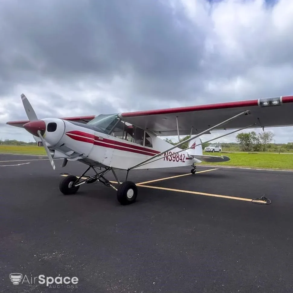A front-quarter view of the white high-wing aircraft N3984Z with red stripes, parked on an asphalt apron.