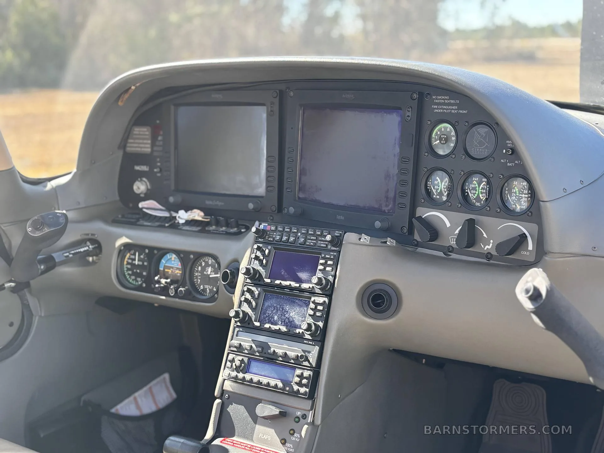 The cockpit of an aircraft showing the instrument panel with multiple screens and controls.