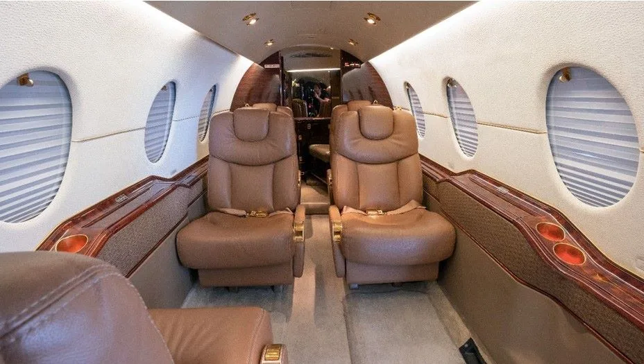 Aircraft interior with four leather seats and wood trim.