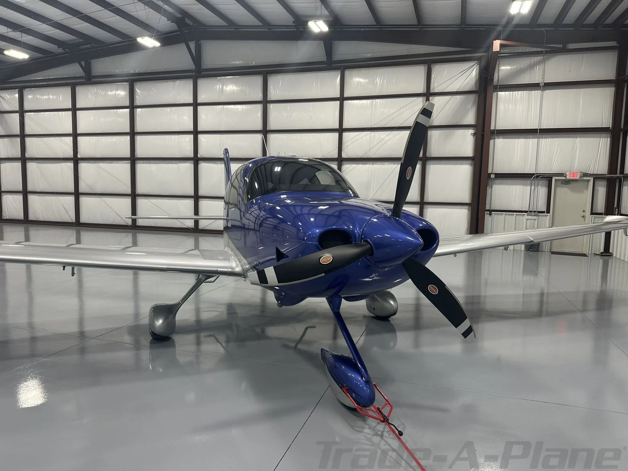 A front view of the blue and silver Cirrus SR22 aircraft N548AR with its propeller tied down in a hangar.