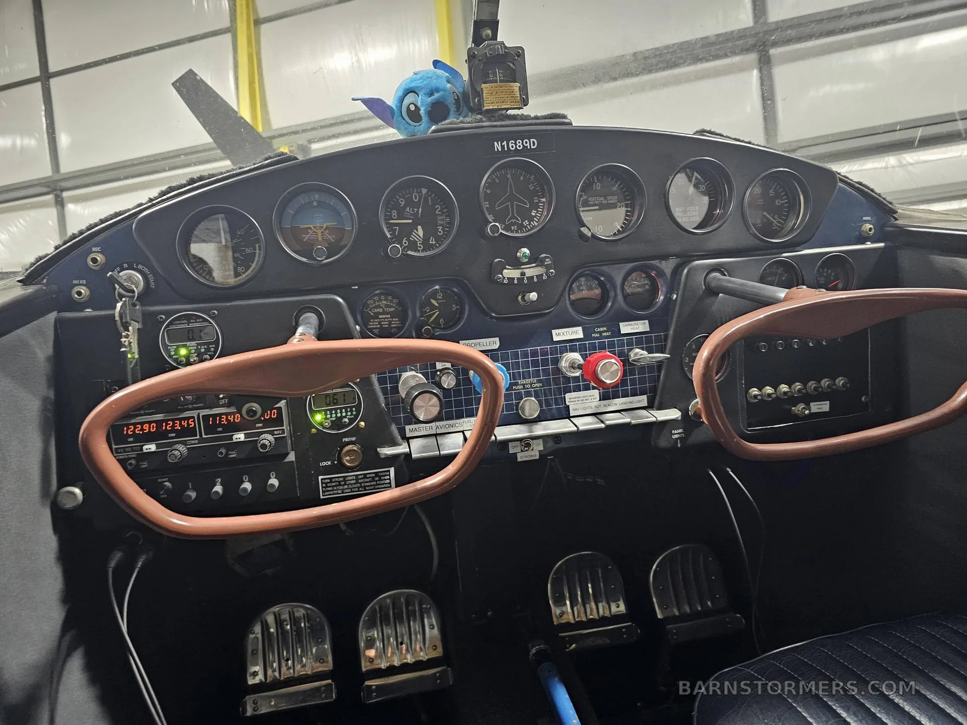 The cockpit of a light aircraft shows the instrument panel, two control yokes, and foot pedals.