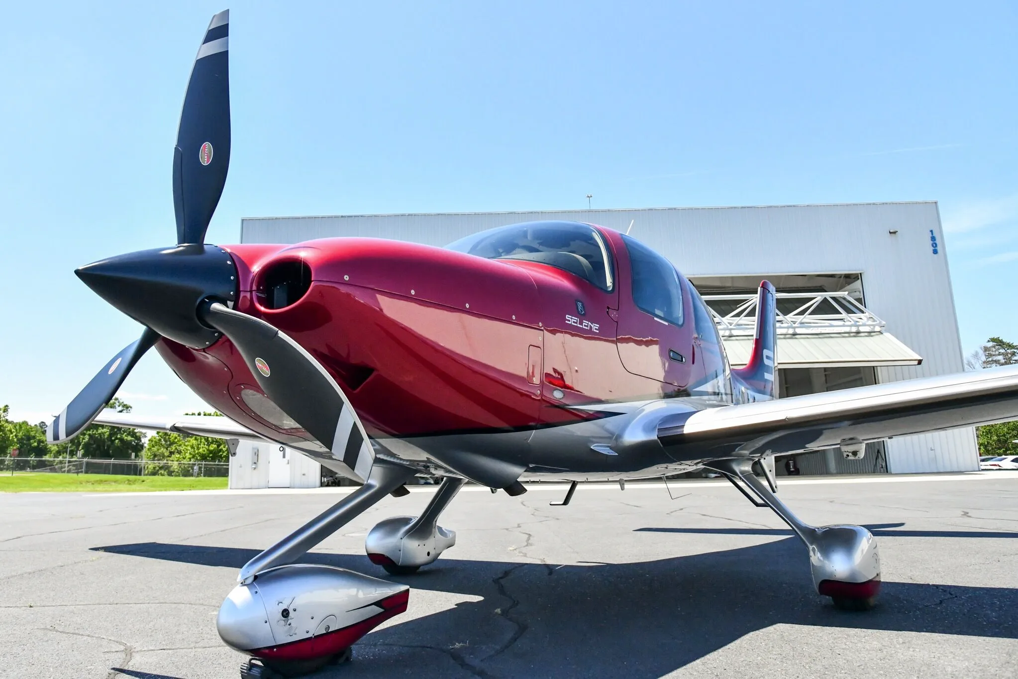 A low-angle front view of a red and white Cirrus SR22T aircraft with registration N918JW parked on an airfield.