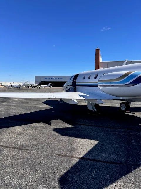 The N700JC business jet parked on the tarmac next to an "Atlantic" hangar, with its main cabin door open.