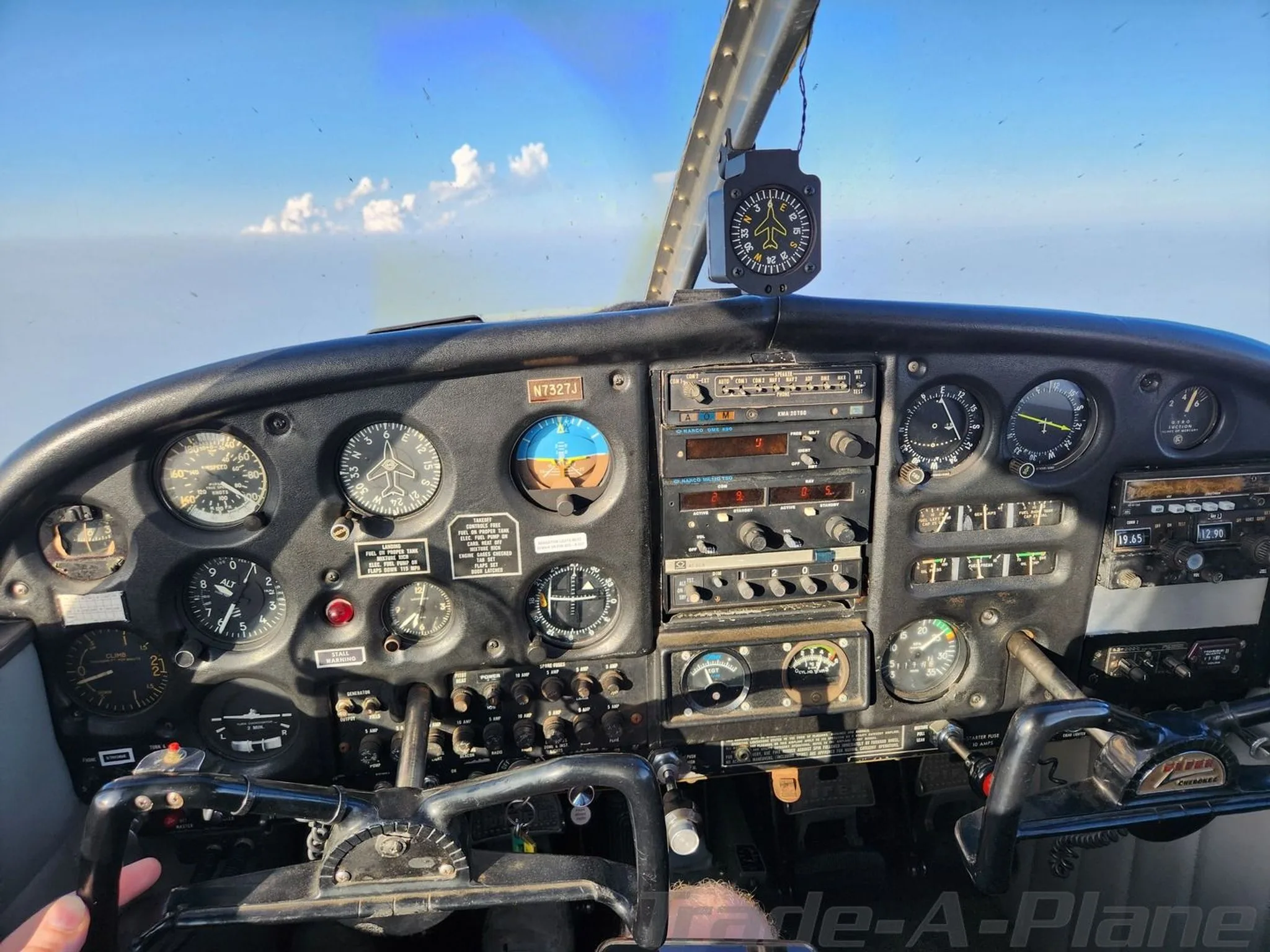The cockpit of a Piper Cherokee 140, N7327J, showing the instrument panel and controls during flight.
