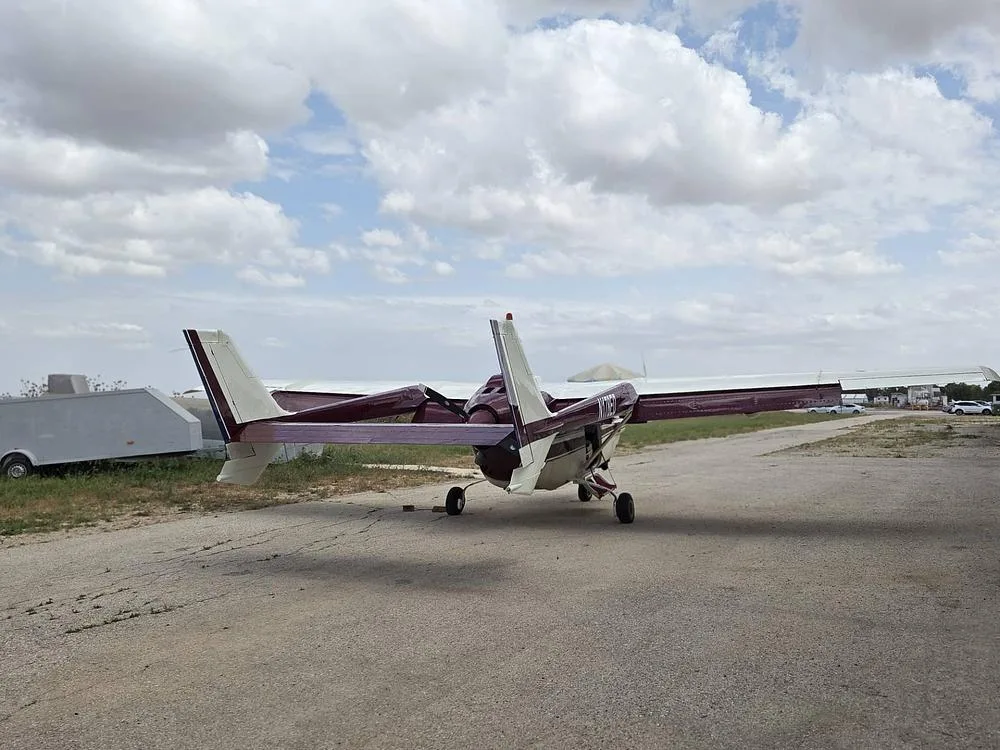 A cream and maroon Cessna 337 Skymaster viewed from the rear-right, parked on an airfield.