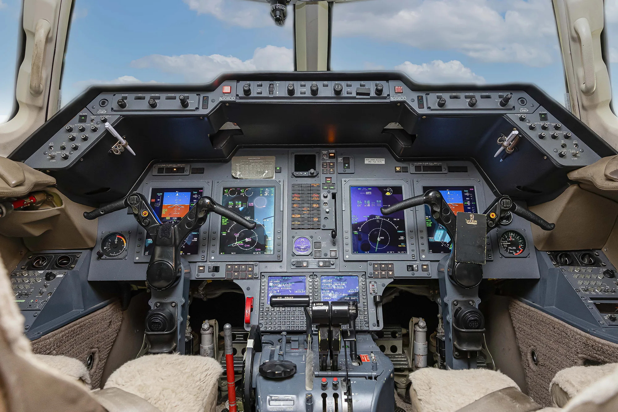 The cockpit of a business jet with multiple digital displays and control yokes.