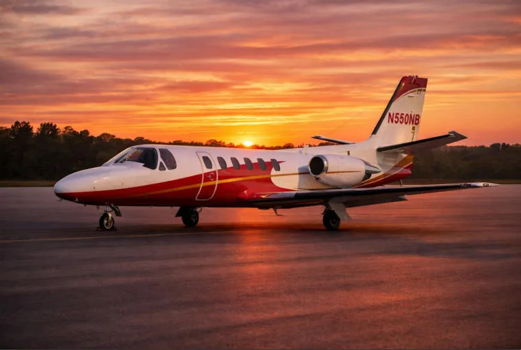 A white and red Cessna Citation business jet, registration N550NB, parked on an airfield at sunset.