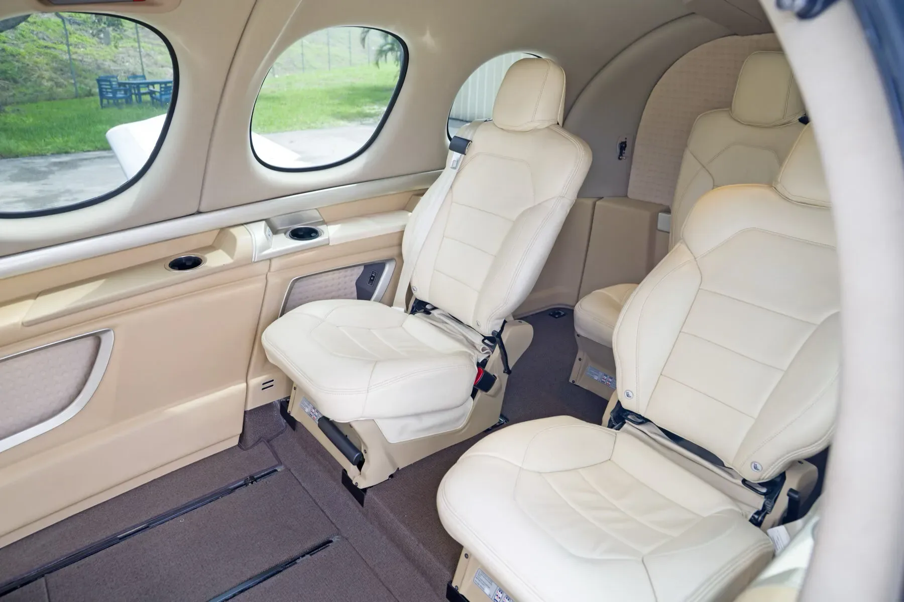 The cream-colored leather passenger seats and side panel with cup holders in the Cirrus Vision Jet cabin.