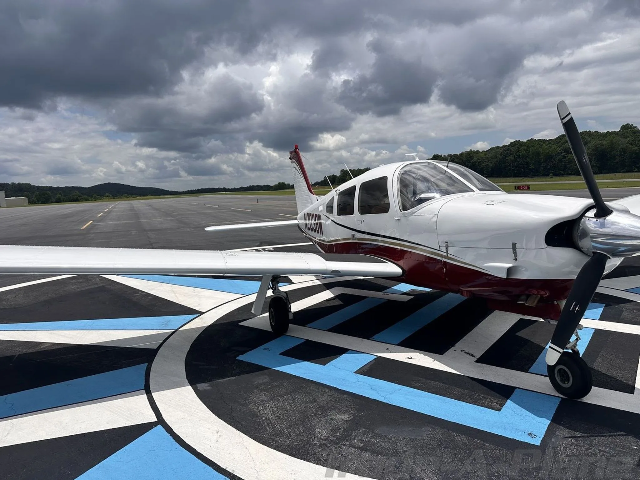 A front-side view of the white and red aircraft N203BW with its propeller, parked on an airport tarmac.