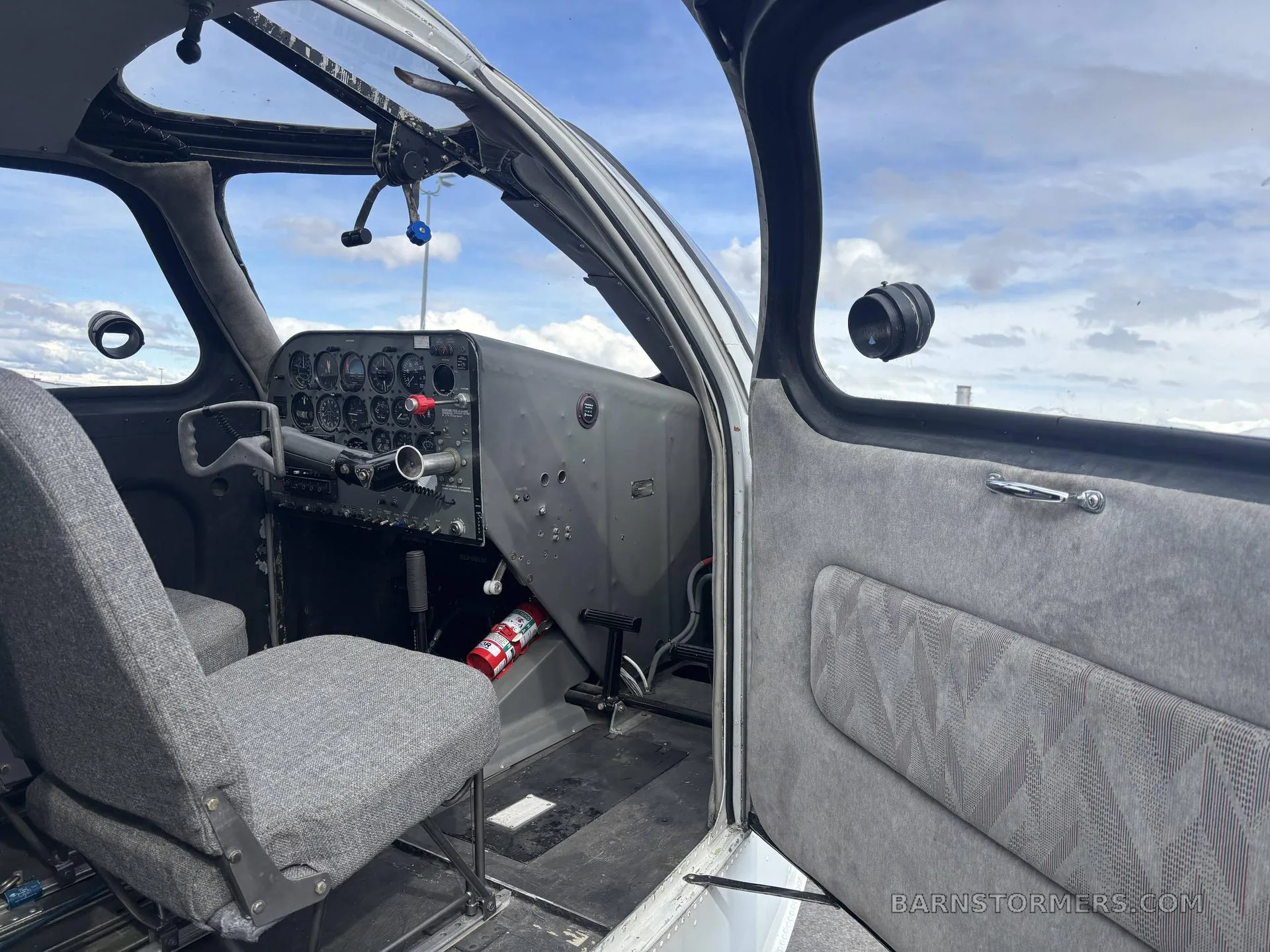 The cockpit of a Republic RC-3 Seabee showing the instrument panel, passenger seat, and open door.