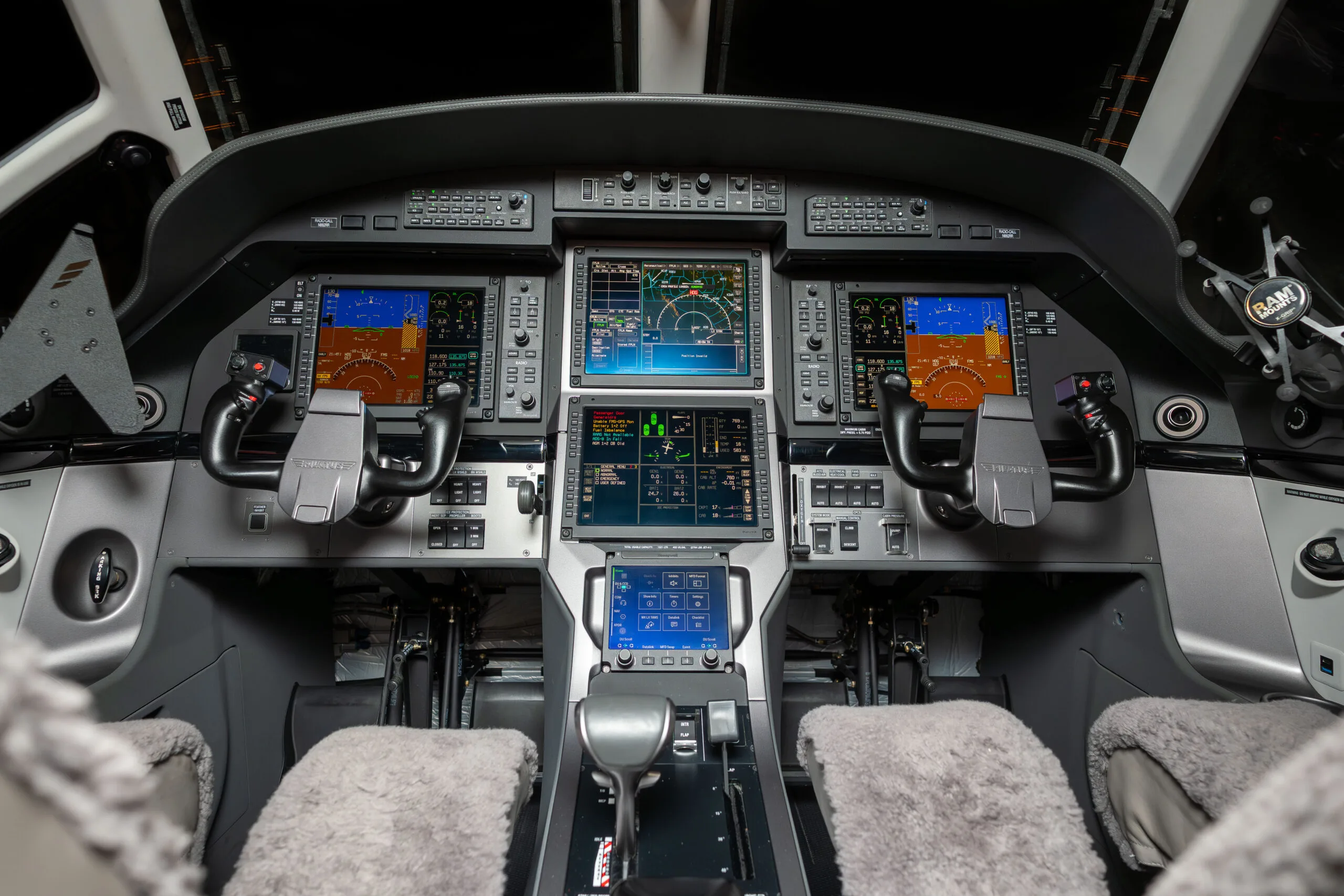 The modern glass cockpit of a Pilatus PC-12 aircraft with multiple display screens and controls.